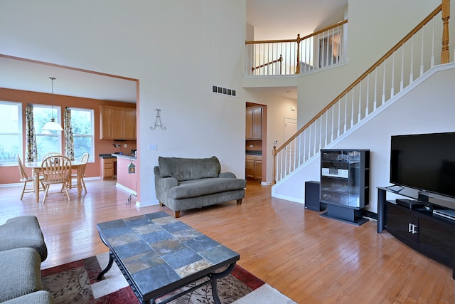 24316 W Bristol Ave, Plainfield, IL 60585 - living room with light wood finished floors, stairway, a towering ceiling, and baseboards