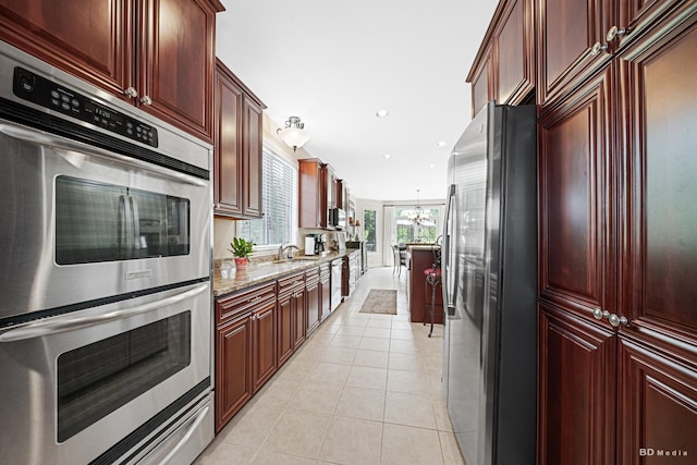 21359 Saddle Ln, Mokena, IL 60448 - kitchen with stainless steel appliances, light tile patterned floors, a chandelier, light stone countertops, and a sink