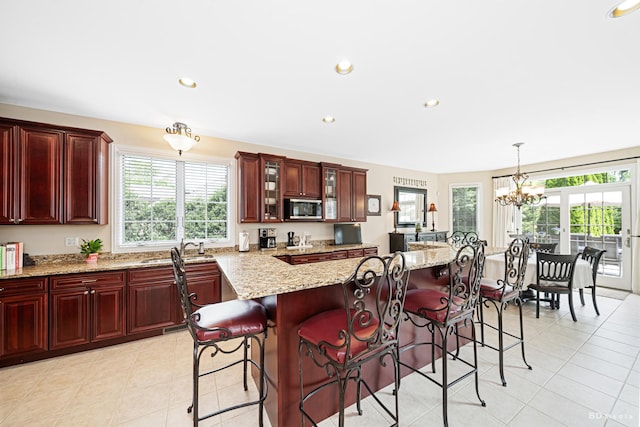21359 Saddle Ln, Mokena, IL 60448 - kitchen with stainless steel microwave, reddish brown cabinets, a sink, light tile patterned floors, and recessed lighting