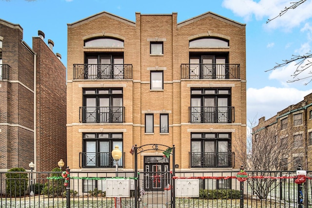 view of front of property featuring brick siding, a balcony, and a fenced front yard