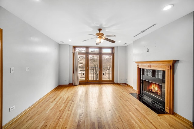unfurnished living room with a ceiling fan, wood finished floors, a tile fireplace, baseboards, and recessed lighting