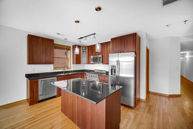 kitchen featuring stainless steel appliances, rail lighting, light wood finished floors, a sink, and baseboards