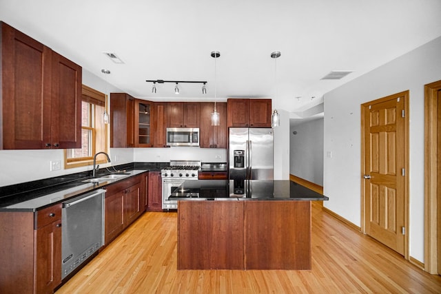 kitchen with stainless steel appliances, a sink, light wood finished floors, and track lighting