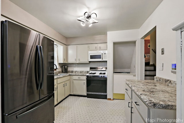 2007 Oak Dr, Mchenry, IL 60050 - kitchen featuring freestanding refrigerator, white microwave, gas range, a sink, and light floors