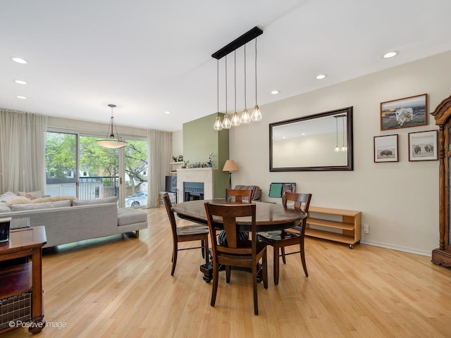 dining space with a fireplace, light wood-style flooring, recessed lighting, and baseboards