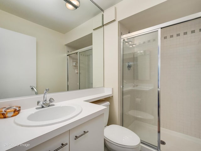 full bath with a stall shower, toilet, and vanity