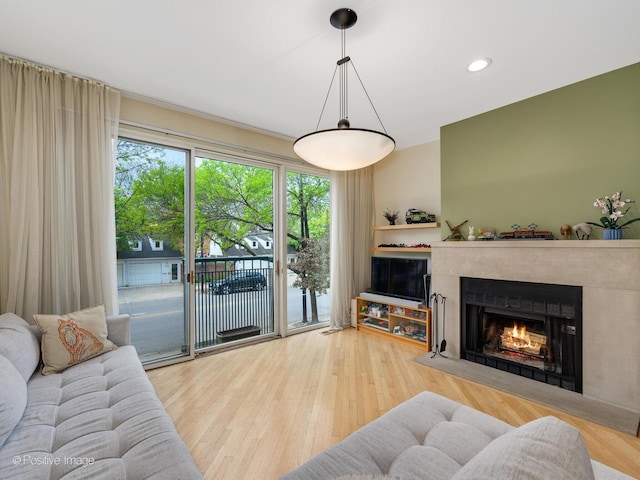 living area featuring a warm lit fireplace, wood finished floors, and recessed lighting