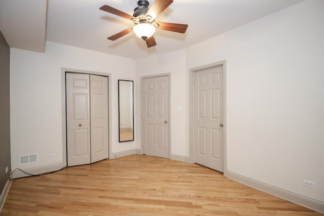 unfurnished bedroom with light wood-type flooring, baseboards, and two closets