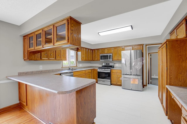 805 Grand Blvd, Joliet, IL 60436 - kitchen featuring stainless steel appliances, a peninsula, a sink, light countertops, and brown cabinetry