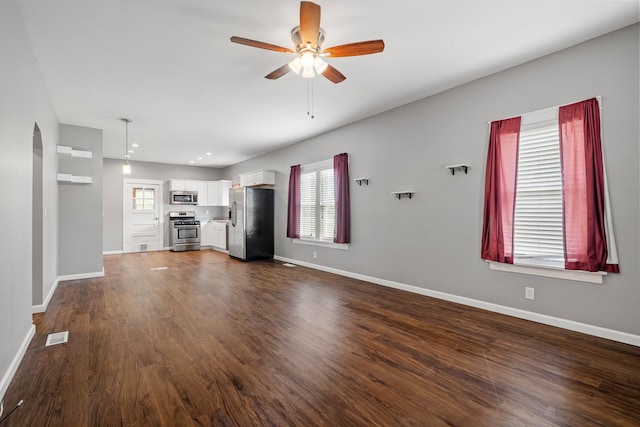 610 Clinton St, Lockport, IL 60441 - unfurnished living room with a ceiling fan, baseboards, dark wood-style flooring, and arched walkways