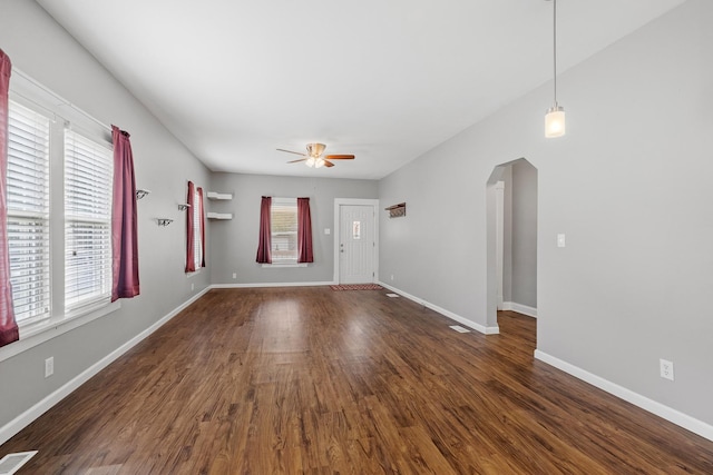 610 Clinton St, Lockport, IL 60441 - unfurnished living room with a ceiling fan, arched walkways, dark wood finished floors, and baseboards