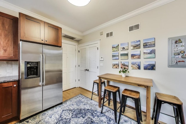 2336 W Roscoe St Unit 3R, Chicago, IL 60618 - kitchen with stainless steel refrigerator with ice dispenser, ornamental molding, light wood-type flooring, and dark stone counters