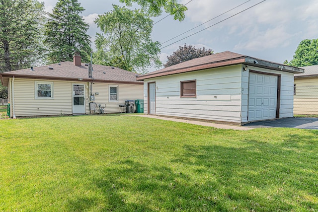 2315 Gilboa Ave, Zion, IL 60099 - rear view of property featuring asphalt driveway, an outdoor structure, a detached garage, and a chimney