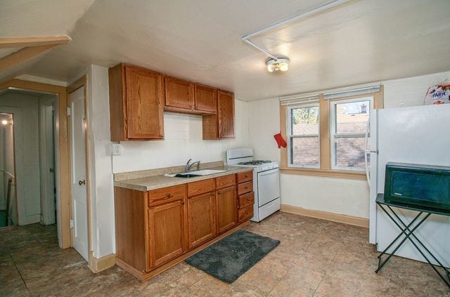 2460 Indiana Ave, Lansing, IL 60438 - kitchen featuring white appliances, a sink, brown cabinetry, and light countertops