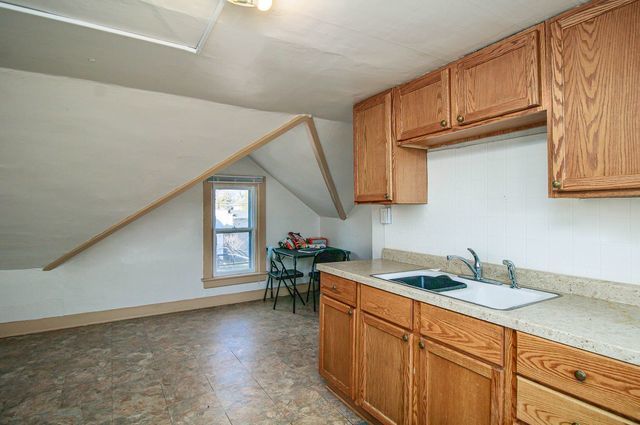2460 Indiana Ave, Lansing, IL 60438 - kitchen with a sink, light countertops, vaulted ceiling, and brown cabinetry
