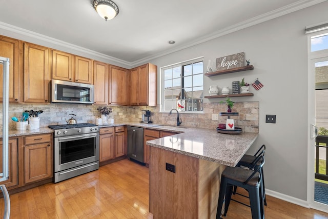 210 Station Park Cir, Grayslake, IL 60030 - kitchen with stainless steel appliances, a sink, a peninsula, a kitchen breakfast bar, and light wood-style flooring