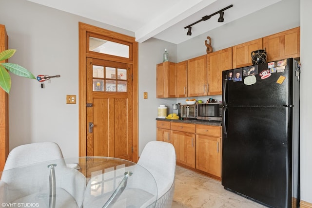 kitchen with freestanding refrigerator, stainless steel microwave, dark countertops, and brown cabinets
