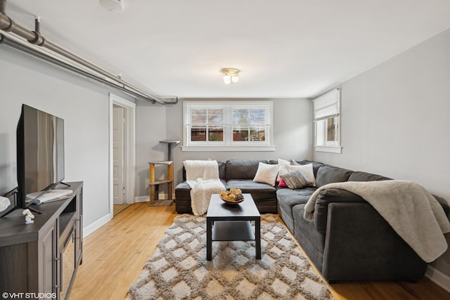 living area featuring healthy amount of natural light, light wood-style flooring, and baseboards