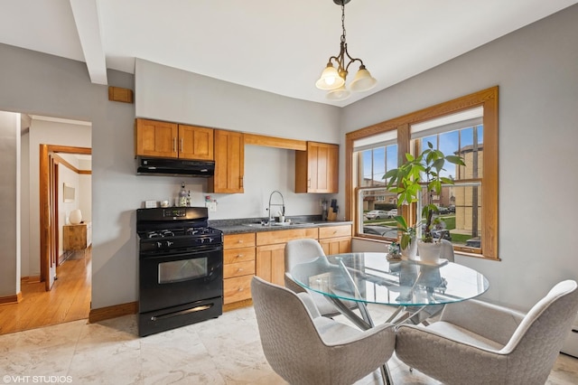 kitchen with black range with gas cooktop, under cabinet range hood, a sink, baseboards, and dark countertops