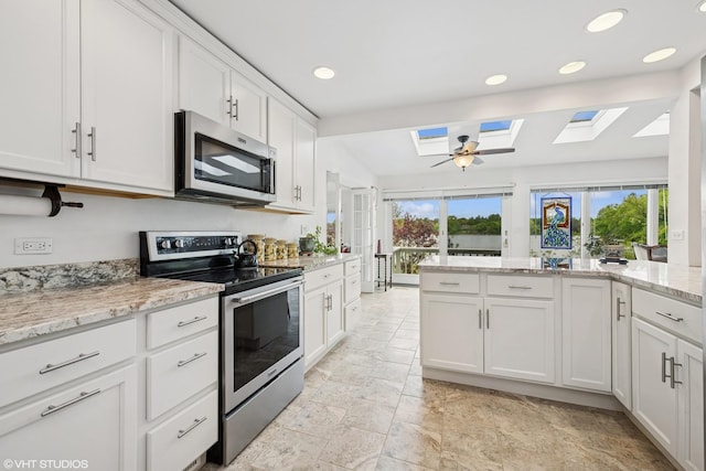 145 W Lake Shore Dr, Tower Lakes, IL 60010 - kitchen with stainless steel appliances, a skylight, white cabinetry, light stone countertops, and recessed lighting