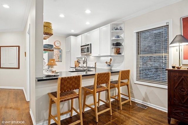 2842 N Southport Ave Unit 2, Chicago, IL 60657 - kitchen with stainless steel microwave, open shelves, dark wood-type flooring, baseboards, and ornamental molding