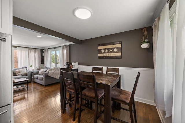dining area featuring dark wood finished floors, wainscoting, and baseboards