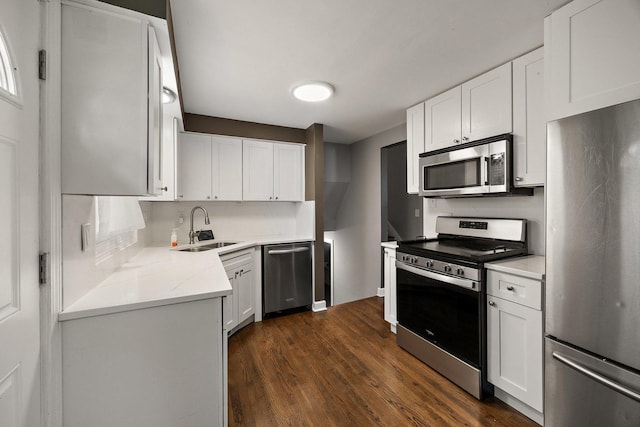 kitchen featuring appliances with stainless steel finishes, a sink, dark wood finished floors, light countertops, and white cabinetry