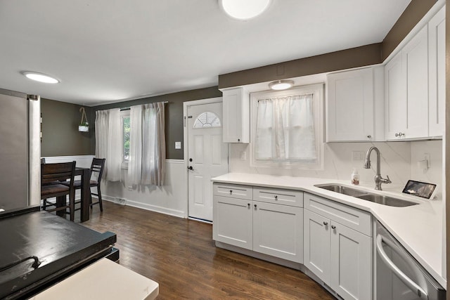 kitchen featuring a sink, dishwasher, light countertops, dark wood finished floors, and white cabinetry
