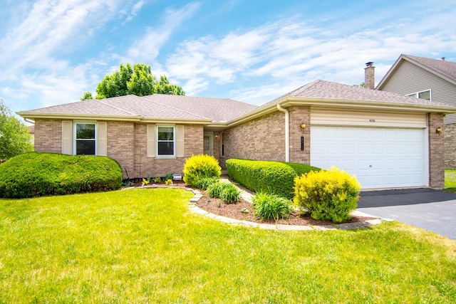 view of front of home featuring brick siding, driveway, a garage, and a front lawn