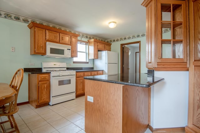kitchen featuring white appliances, brown cabinets, a peninsula, light tile patterned floors, and dark stone counters