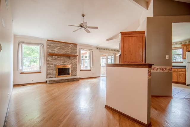 unfurnished living room with lofted ceiling, a ceiling fan, healthy amount of natural light, and light wood-style floors