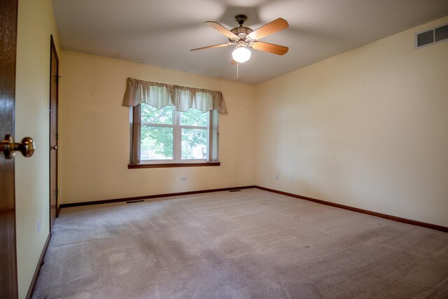 carpeted spare room with a ceiling fan and baseboards