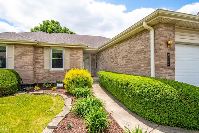 property entrance with brick siding, a garage, and roof with shingles