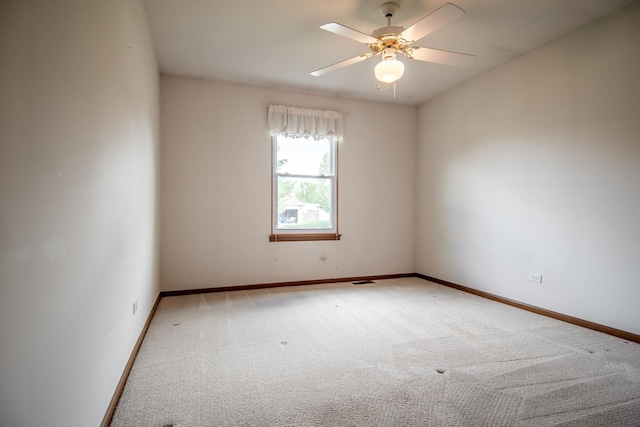 carpeted spare room with baseboards and a ceiling fan