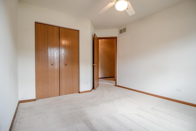 unfurnished bedroom featuring light colored carpet, a closet, baseboards, and a ceiling fan