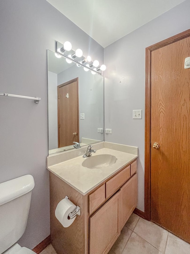 bathroom with toilet, vanity, and tile patterned flooring