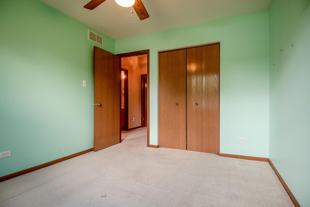 unfurnished bedroom featuring a closet, light colored carpet, baseboards, and ceiling fan