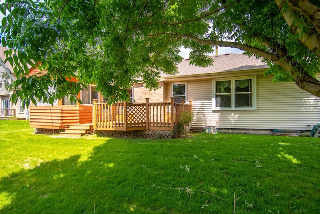 rear view of property with a deck, a lawn, and roof with shingles