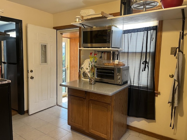 2256 S 15th Ave, North Riverside, IL 60546 - kitchen with stainless steel microwave, light tile patterned floors, brown cabinets, and baseboards