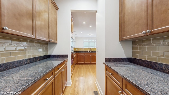 1416 S Emerald Ave, Chicago, IL 60607 - kitchen with light wood finished floors, dark stone countertops, tasteful backsplash, a sink, and brown cabinetry
