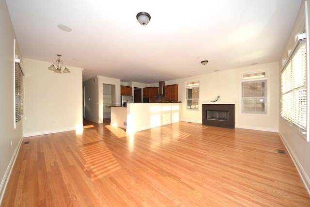 1416 S Emerald Ave, Chicago, IL 60607 - unfurnished living room with a chandelier, light wood-style floors, a fireplace, and baseboards