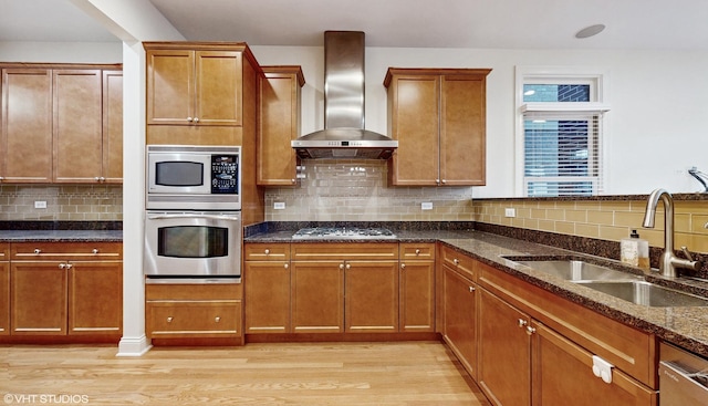 1416 S Emerald Ave, Chicago, IL 60607 - kitchen featuring stainless steel appliances, wall chimney exhaust hood, a sink, light wood-style floors, and dark stone countertops