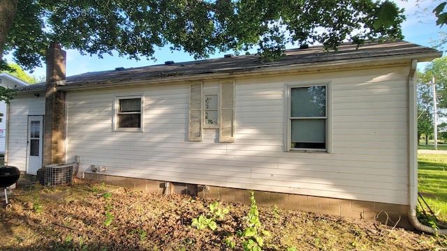 view of side of home with a chimney and central AC