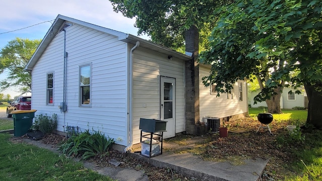 view of side of home featuring central AC unit and a chimney