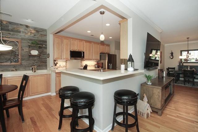 12370 Russet Ln, Huntley, IL 60142 - kitchen featuring appliances with stainless steel finishes, light brown cabinetry, a kitchen bar, light wood-style flooring, and crown molding