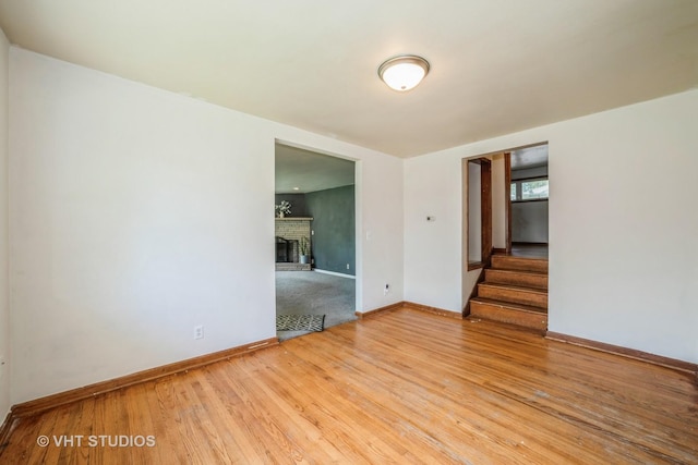 880 Marcella Rd, Merrillville, IN 46410 - spare room featuring stairway, wood finished floors, baseboards, and a brick fireplace