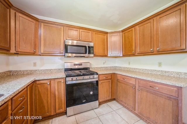 880 Marcella Rd, Merrillville, IN 46410 - kitchen with stainless steel appliances, brown cabinets, and light tile patterned flooring