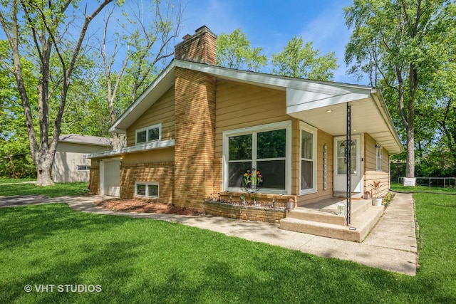 880 Marcella Rd, Merrillville, IN 46410 - back of house featuring a chimney, brick siding, a lawn, and an attached garage