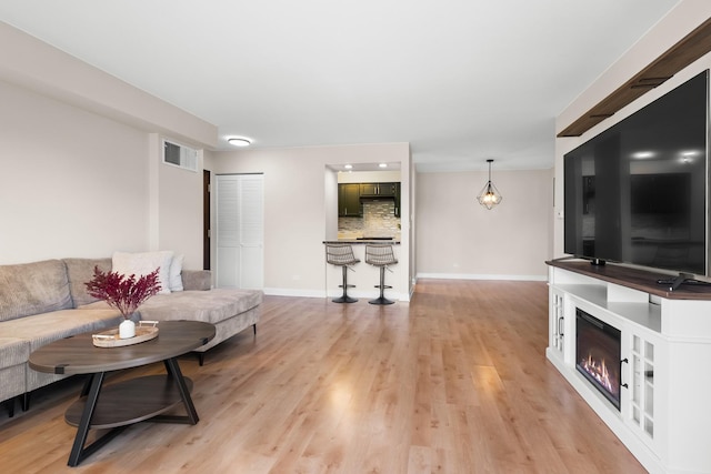 812 N River Rd Unit 3B, Mount Prospect, IL 60056 - living area featuring a glass covered fireplace, light wood-type flooring, and baseboards