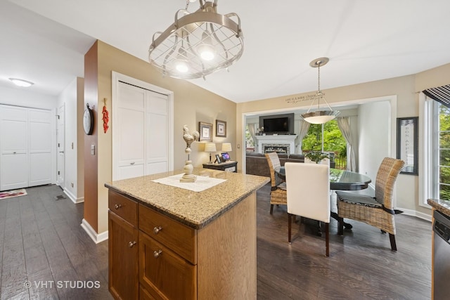 2260 Brookside Ct, Aurora, IL 60502 - kitchen featuring dark wood-type flooring, a center island, brown cabinetry, a fireplace, and decorative light fixtures